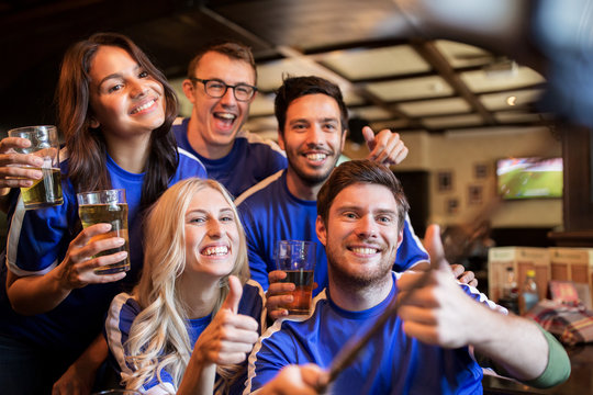 football fans with beer taking selfie at pub