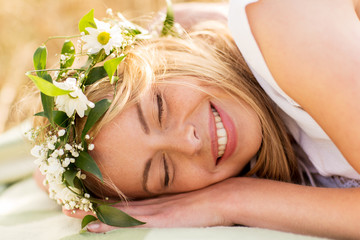 Obraz na płótnie Canvas happy woman in wreath of flowers lying