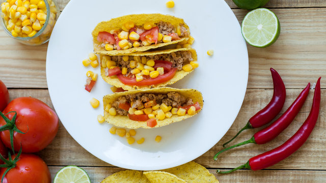 Spicy mexican tacos baked with chicken meat, corn and tomatoes and served on a white plate