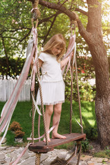Little girl having fun on a swing outdoor. Child playing, garden playground.