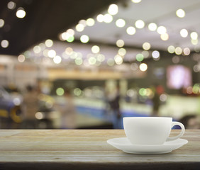 White cup on wooden table over blur of shopping mall