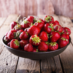 Fresh strawberries on a metal plate and an old wooden background.Healthy food or diet concept. Vintage style.selective focus.