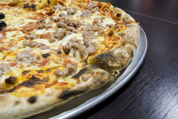 pizza with sausage, mozzarella and tomato over wooden table
