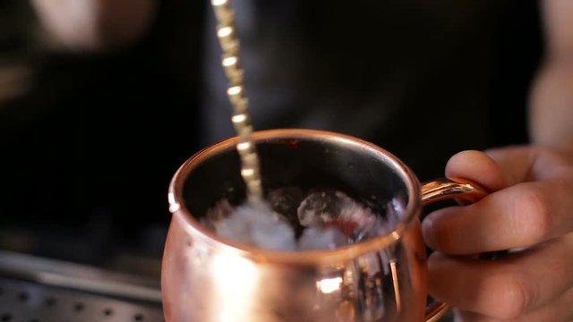 The bartender mixes a cocktail in a copper bowl