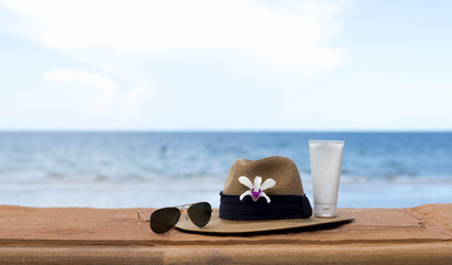 Fototapeta na wymiar sunglasses and hat and sunblock with flower on the sea
