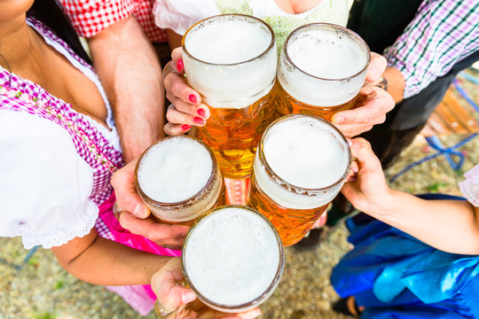 Anstoßen mit Bier in Maßkrügen im Biergarten, Close-up auf fünf Biergläser