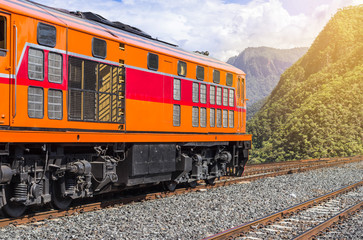 Obraz premium orange diesel engine locomotive passenger train crossing valley mountains 