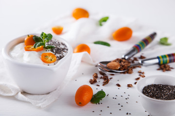 Yogurt with kumquats ,Chia seeds,and granola on a white background.Healthy food or diet concept.selective focus.