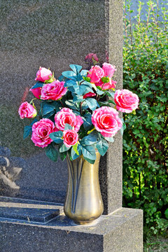 Kunstblumen mit Vase am Grabstein