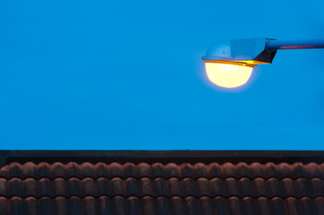 Glowing street lamp under blue-hour sky