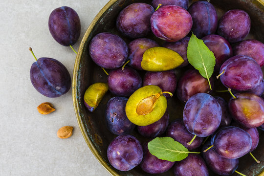 Ripe plums in a old bowl on a gray stone background. 