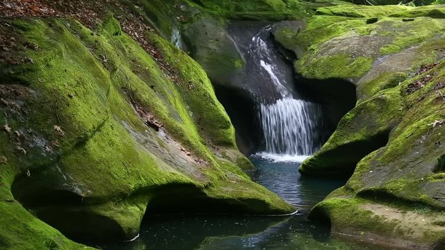 Water plunges into a mossy channel carved into the rock above Robinson Falls in the Hocking Hills of Ohio. Looping.