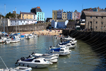 Tenby, Wales. August 2016. A hot August day with bathers in the sea, boats in the foreground and brightly coloured houses and hotels in the background
