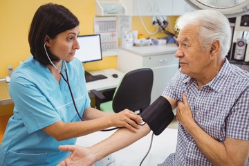 Female doctor checking blood pressure of patient