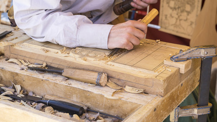 craftsman carving wood in a medieval fair, carpentry tools