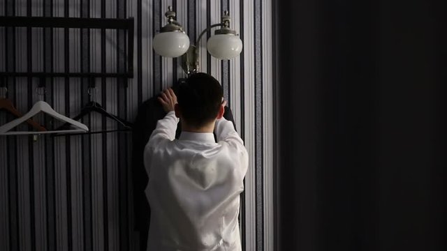 Stylish business man takes off his jacket from the hanger in the strict interior