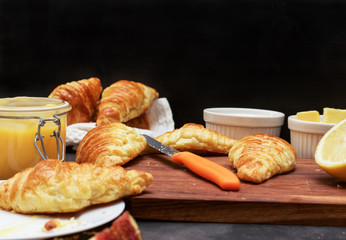 Croissants and lemon kurd on a black wooden background, selective focus