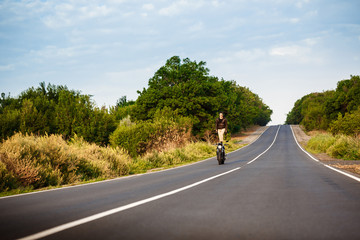 Young man riding on motorbike, doing tricks at countryside road.