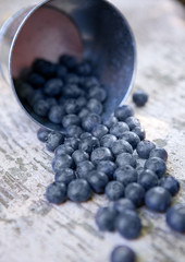 Blueberries in small steel bucket on grunge wooden board