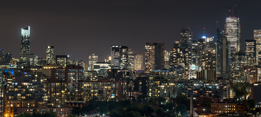 Fototapeta premium Urban lighted landscape of Toronto. A balcony view of lighted streets, parks, buildings and office towers on a hot & humid August night in capitol of Ontario, Canada.
