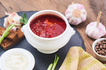 Red borsch in white plate and bacon with garlic on a stone Board