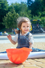 Little baby girl builder with the construction helmet and poster