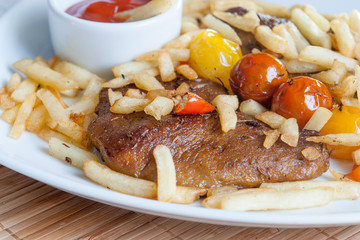 Vegetarian steak made from vegan seitan, cherry tomatoes and fries