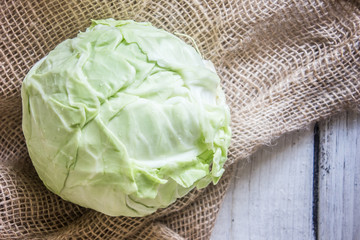 Head of cabbage on sackcloth, white wooden table