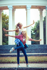 Two young girl friends together in hug at park