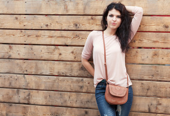 Beautiful brunette girl stands near a wall wooden planks