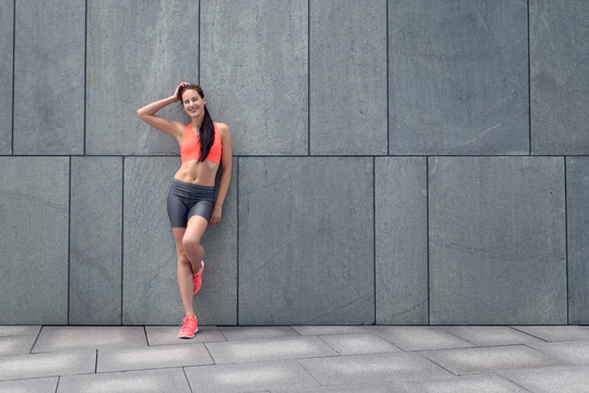Attraktive sportliche Frau lehnt an der Wand
