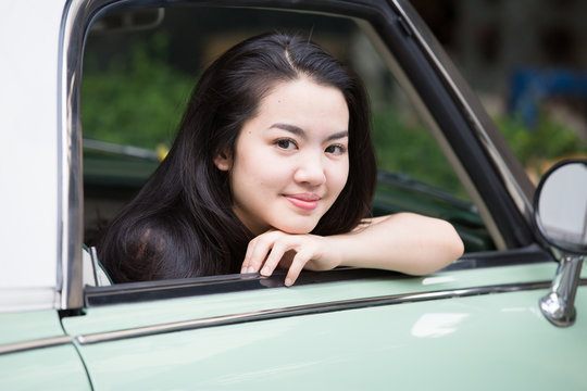 Asian lady smiling in a vintage car