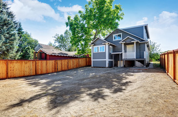 Empty backyard ground ready for design. Blue siding trim house