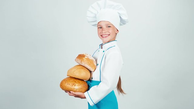 Young baker holds three loaves of bread and looking at camera isolated on white background