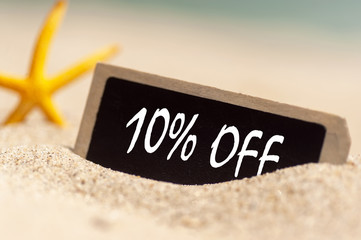 wooden board on sunny sandy beach  with text 10% off