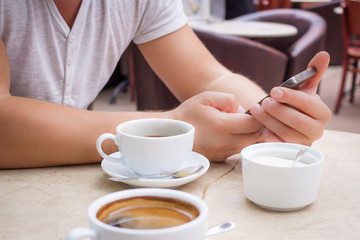 Man with smartphone at marble table with cup of coffee