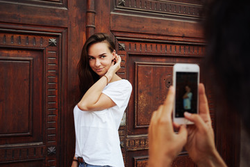 An attractive young girl is posing at camera of a mobile phone while standing beside the massive...