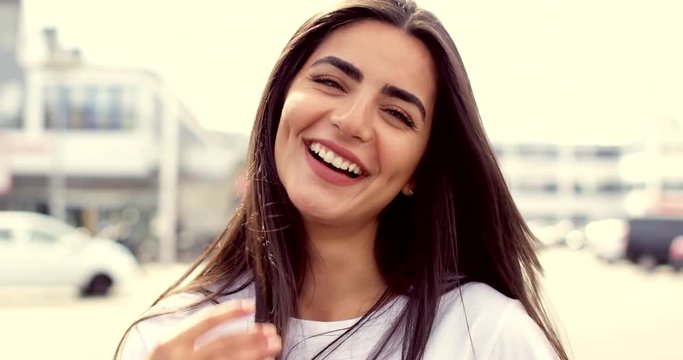 Woman laughing and smiling at camera, standing in big city urban environment