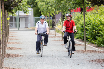 Smiling Senior Couple Cycling In Park