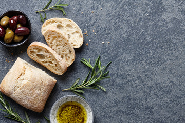 Italian food background with ciabatta bread, olive oil, olives and rosemary