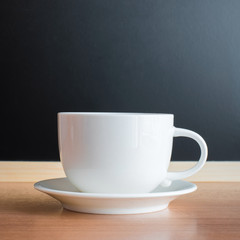 white cup and saucer on wood table