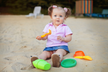 little baby plays with toys on the sand. The concept of education and child development.