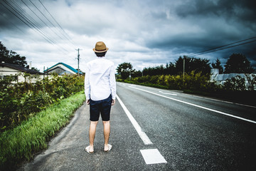 まっすぐな道路を歩く男性