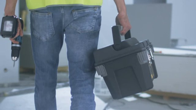Construction Worker Walking inside Building Under Construction and Carrying Toolbox. Shot on RED Cinema Camera in 4K (UHD).