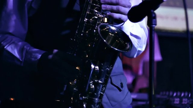 Saxophonist performs a melody, standing on the stage.