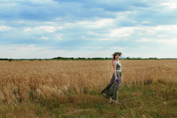 Naklejka na ściany i meble beautiful girl in a wheat field with wreath on head