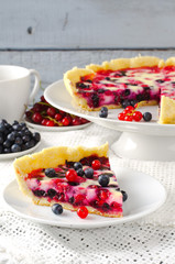 Mix berry tart, pie, cake with raspberries, bilberries, bluberries, red currant and cream on white background