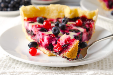 Mix berry tart, pie, cake with raspberries, bilberries, bluberries, red currant and cream on white background