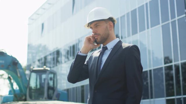 Businessman in Hard Hat Talking on the Phone on Construction Site. Shot on RED Cinema Camera in 4K (UHD).