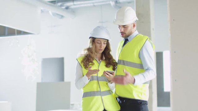 Male and Female Engineers in Hard Hats Having Conversation inside a Building under Construction. Shot on RED Cinema Camera in 4K (UHD).